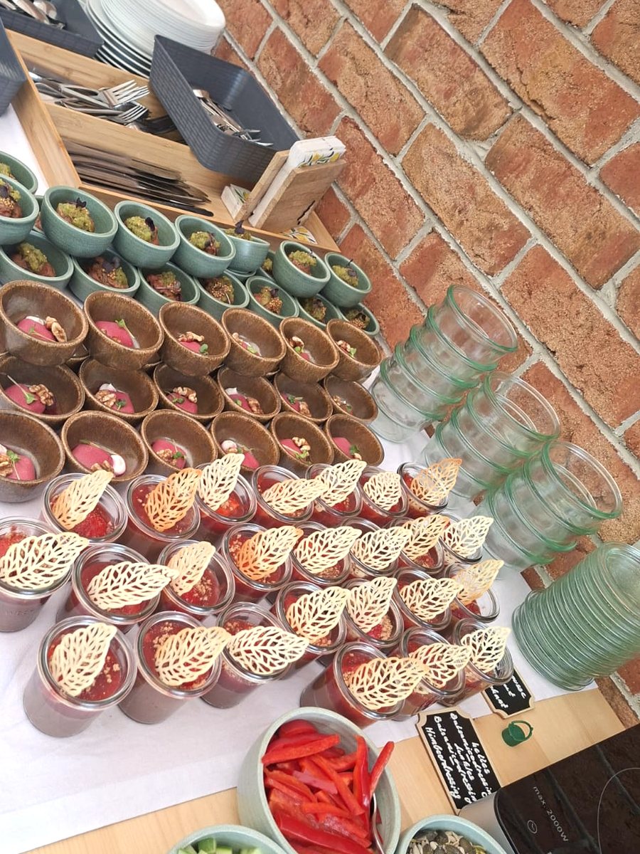 Buffettisch schräg von oben mit Fingerfood-Reihen, Gläsern und Salatschälchen