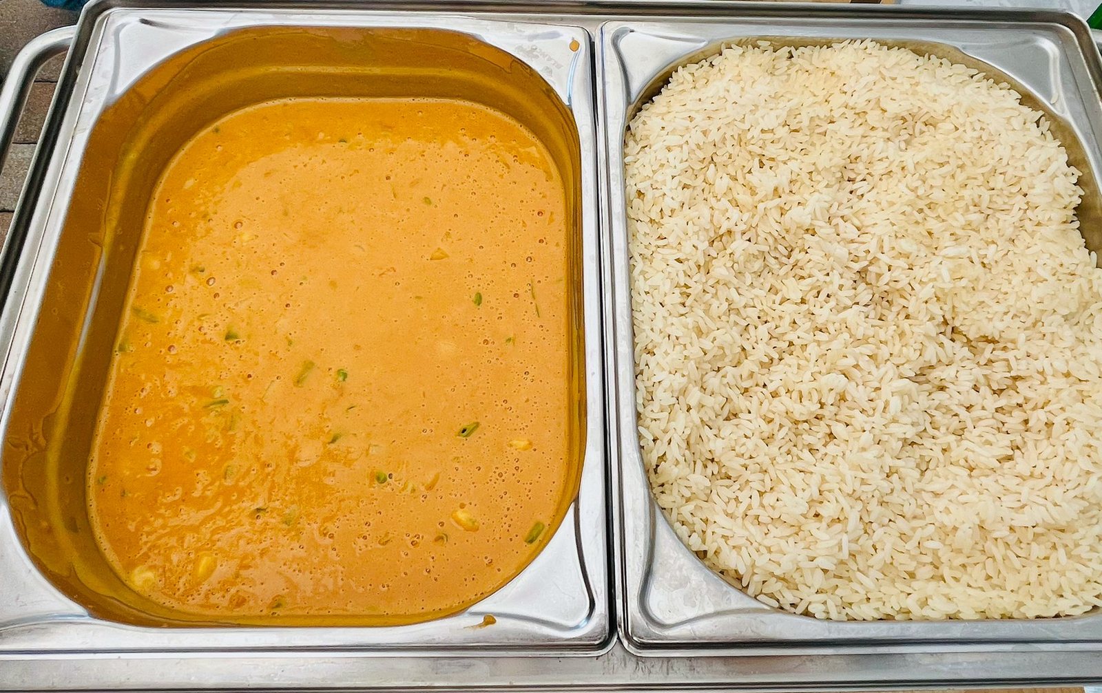 Gastronorm-Behälter mit cremiger Currysauce und Reis auf einem Chafing Dish