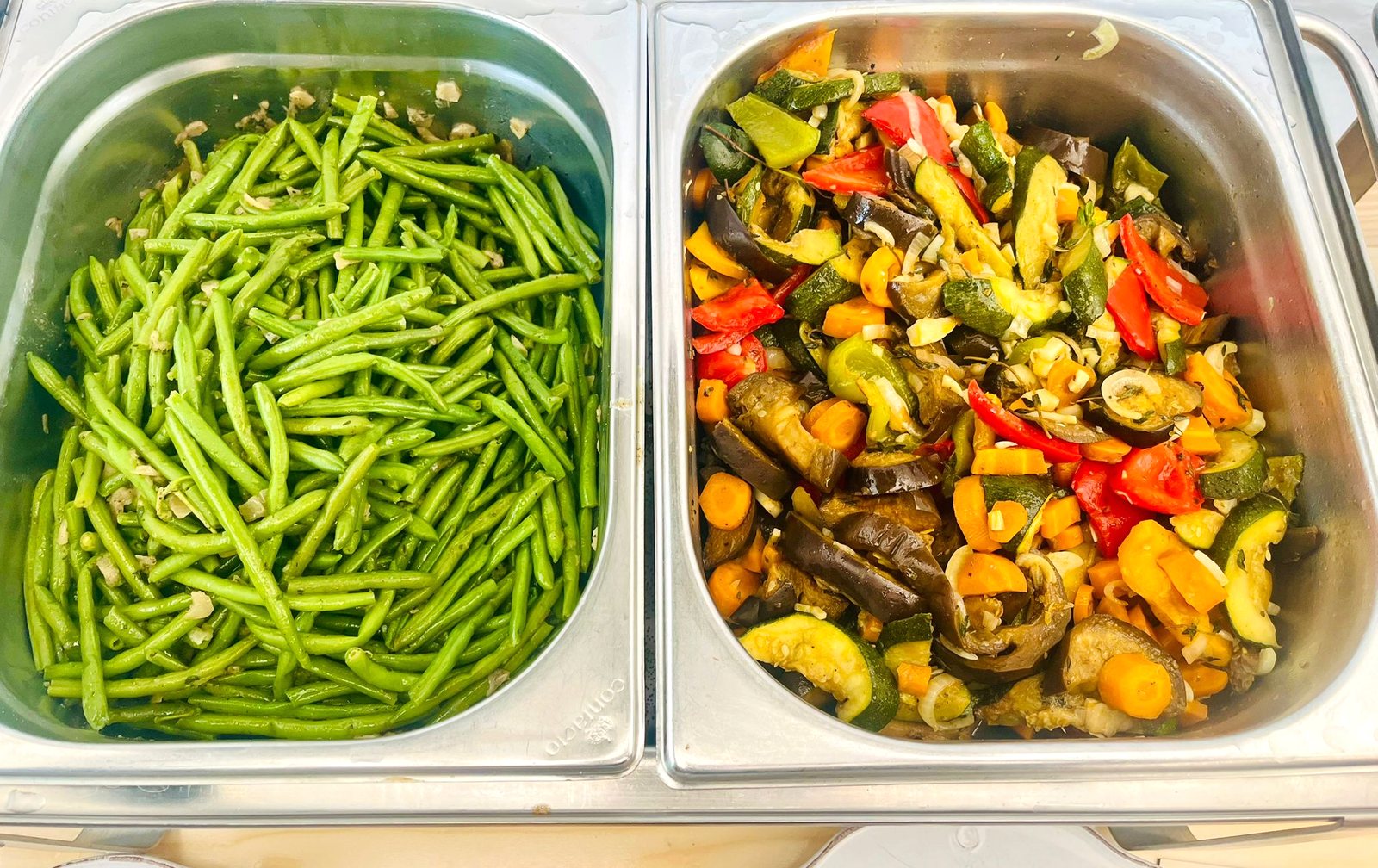 Gastronorm-Behälter mit grünen Bohnen und buntem Ratatouille-Gemüse aus Zucchini, Aubergine, Paprika und Karotte
