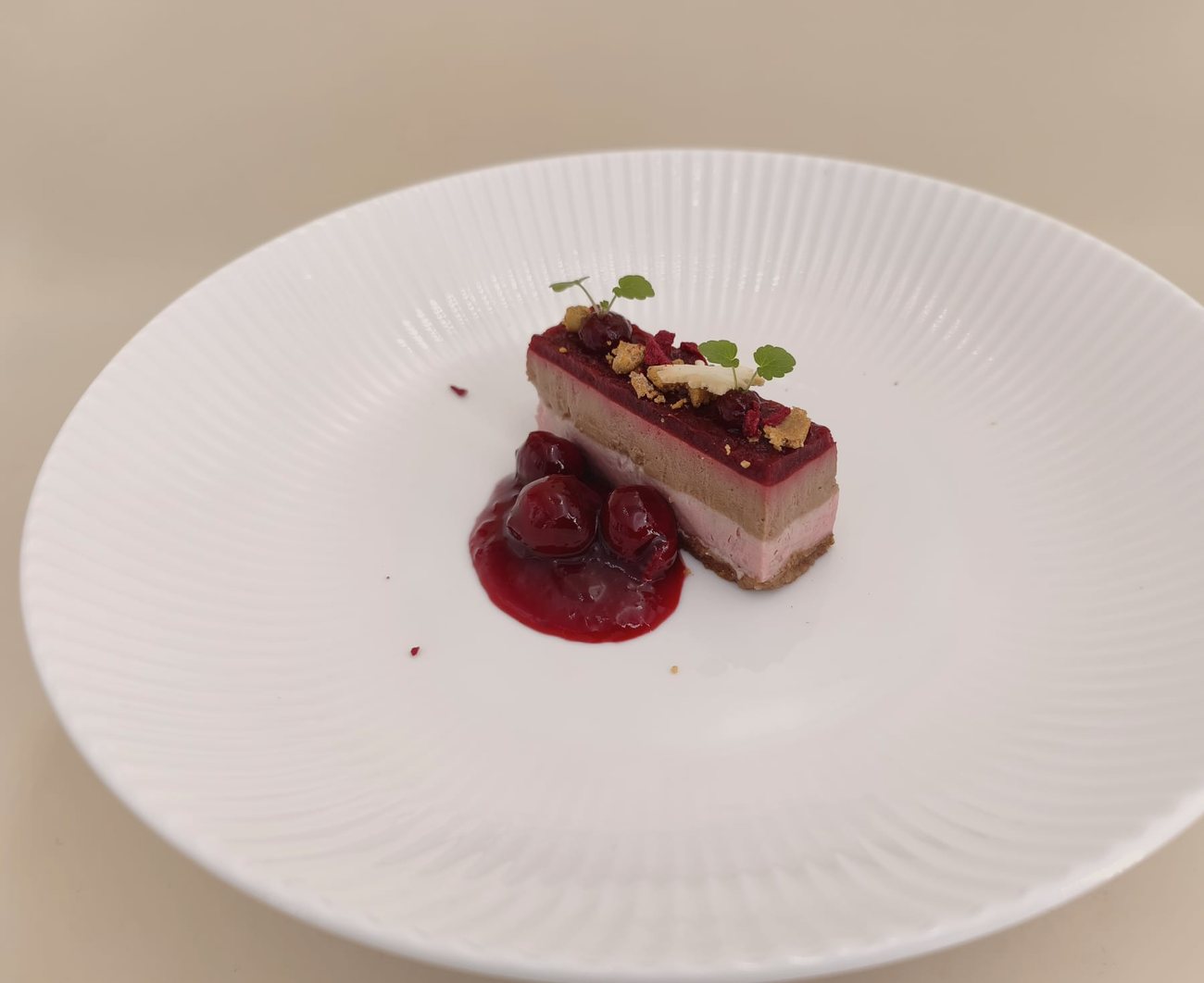 Kirsch-Schokoladen-Schnitte mit Kirschkompott, Krokant und Kresse auf weißem Rillenteller