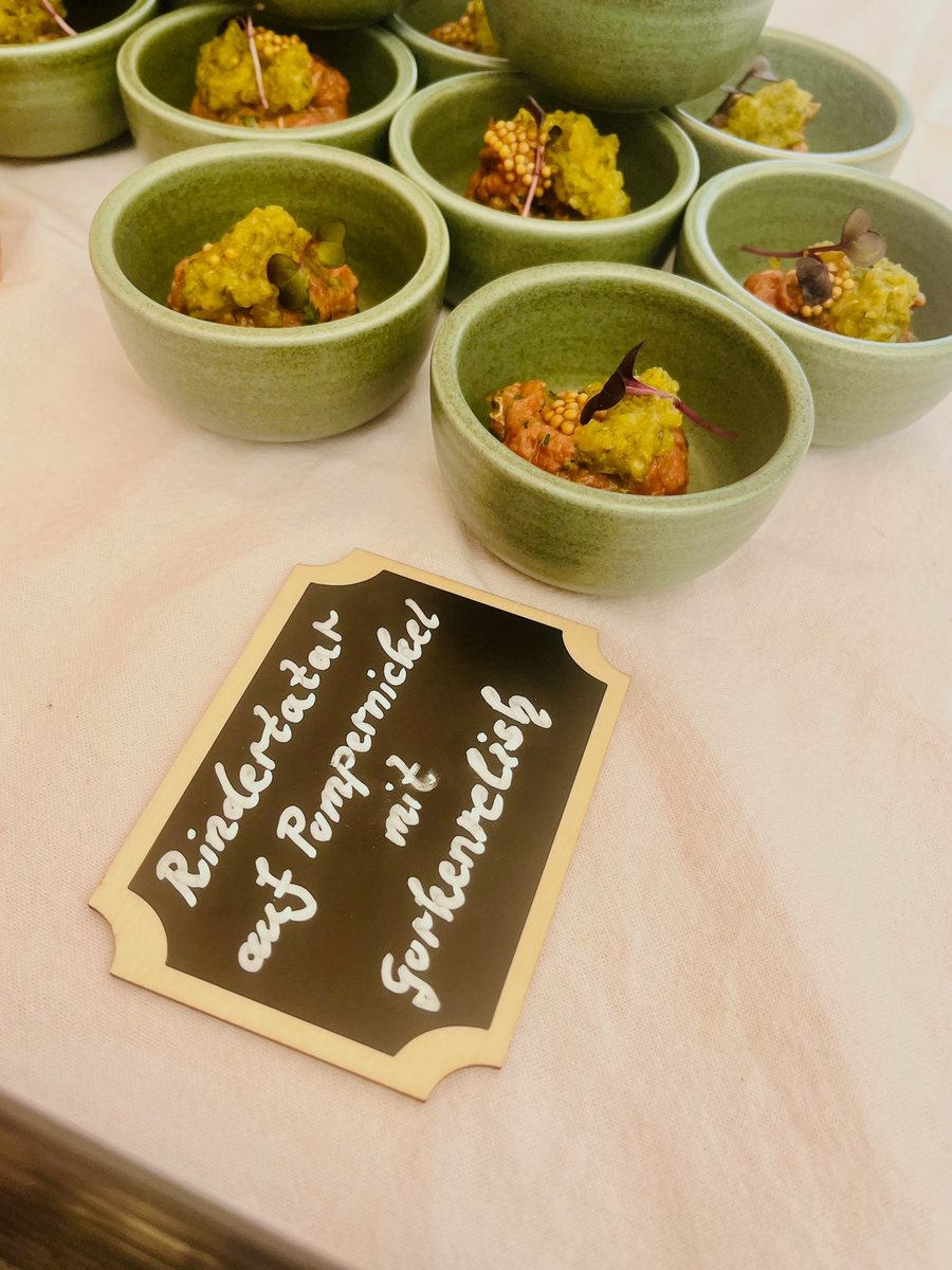 Grüne Steingutschälchen mit Rindertatar und Gurkenrelish, davor eine handbeschriebene Kreidetafel