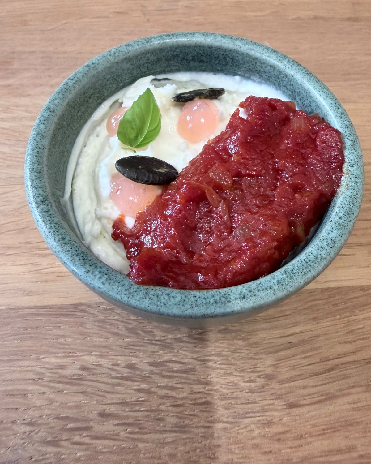 Tomaten-Confit auf Burrata-Creme mit Basilikum, Oliven und Tomatengel in grauer Steingutschale