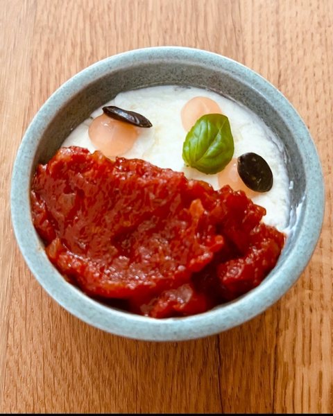 Tomaten-Confit auf Burrata-Creme mit Basilikum, Oliven-Gel und Kürbiskernen in grün-grauer Steingutschale